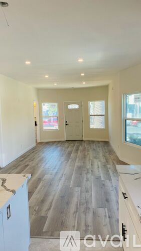 A spacious room with wooden flooring and white walls.