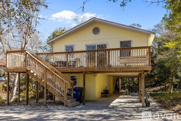 A yellow house with a balcony and stairs leading to the entrance.
