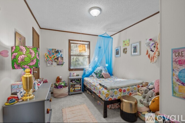 A bedroom with a bed, a dresser, and a window with a blue curtain.
