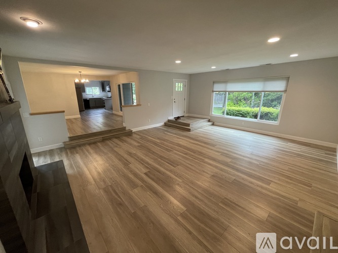 A spacious room with wooden flooring and a large window.