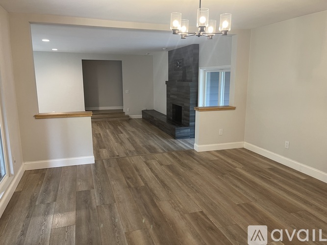 A spacious living room with wood flooring and a fireplace.