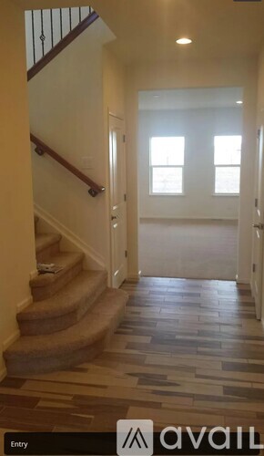 A hallway with a staircase and a tiled floor.