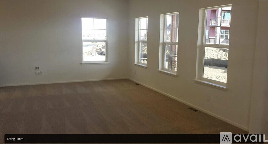 A living room with three windows and wooden flooring.