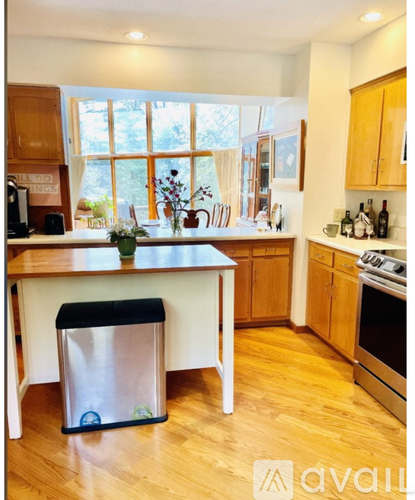 A kitchen with wooden cabinets and a white island with a trash can.