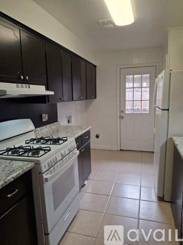 A kitchen with a white stove top oven and black cabinets.