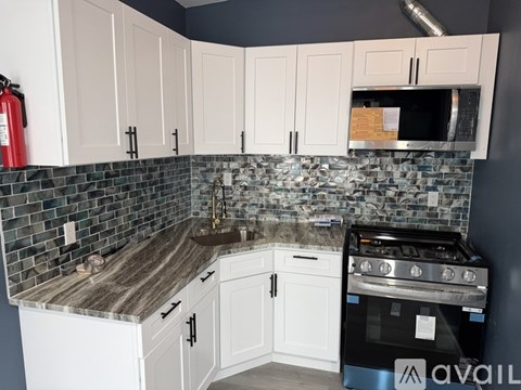 A kitchen with white cabinets and a black stove top oven.