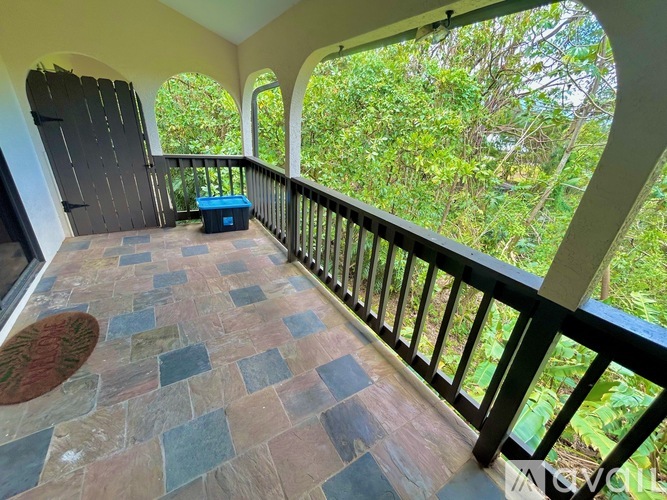 A balcony with a stone floor and a view of trees.