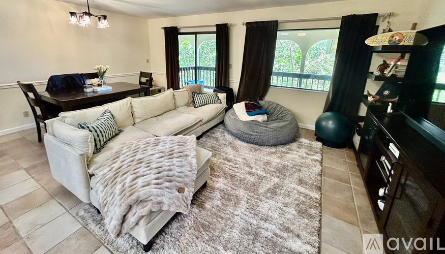 A living room with a couch, a chair, a rug, and a dining table.