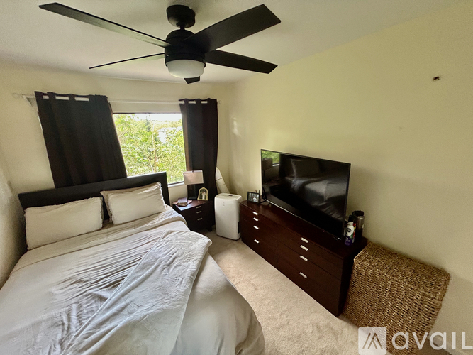 A bedroom with a bed, a ceiling fan, and a television.