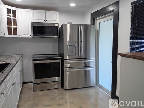 A kitchen with a stainless steel refrigerator, oven, and microwave.