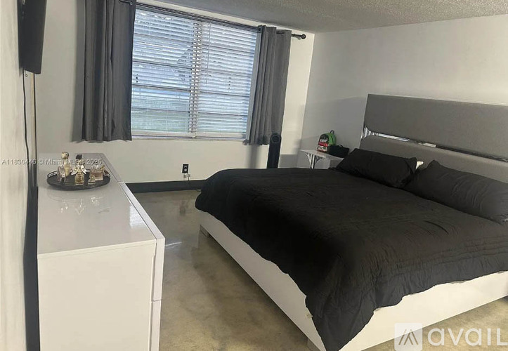 A bedroom with a bed, nightstand, and window with blinds.