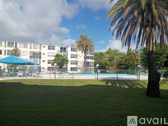 A palm tree stands in front of a building with a pool.