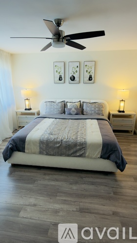 A bedroom with a bed, two lamps, and a ceiling fan.