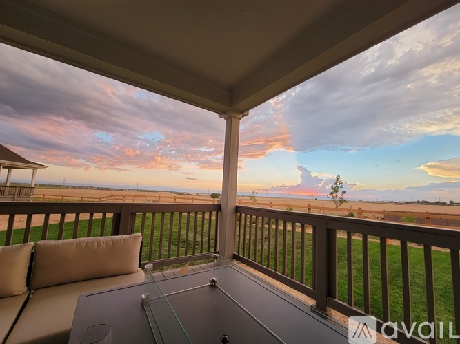 A balcony with a table and chairs overlooking a field.