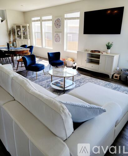 A living room with a white couch and a television mounted on the wall.