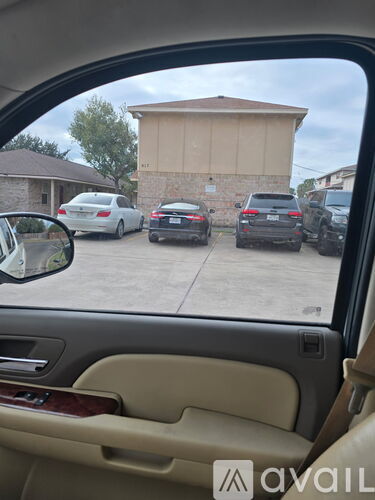 A car is parked in a lot with a building in the background.