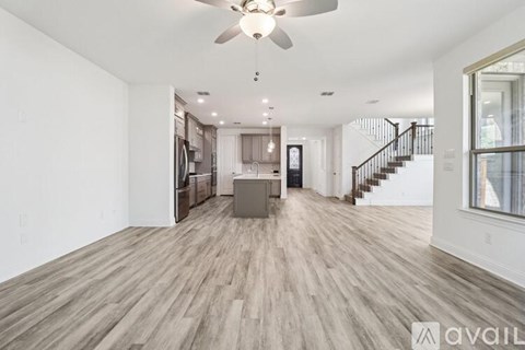 A spacious living room with a ceiling fan and lighting fixtures.