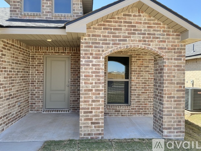 A house with a grey door and a window with a brick wall.