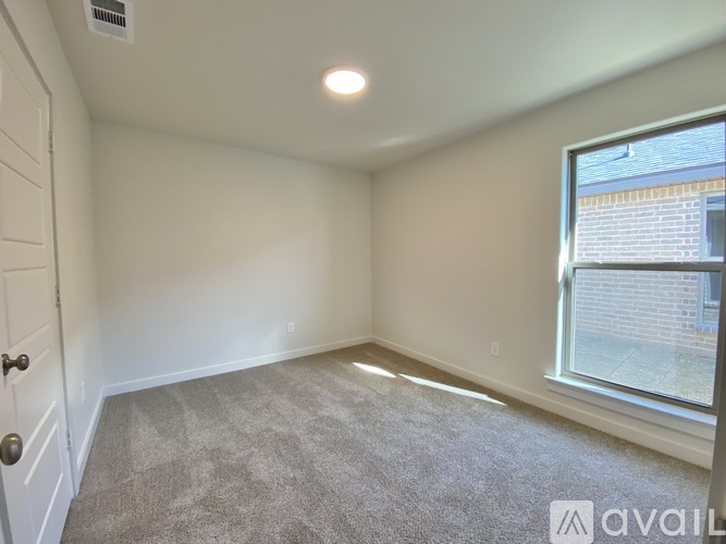 A room with a carpeted floor and a window showing a building outside.