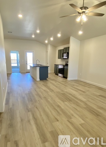 A spacious room with wooden flooring and a ceiling fan.