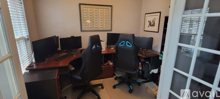A room with a desk and chairs with a computer on it.