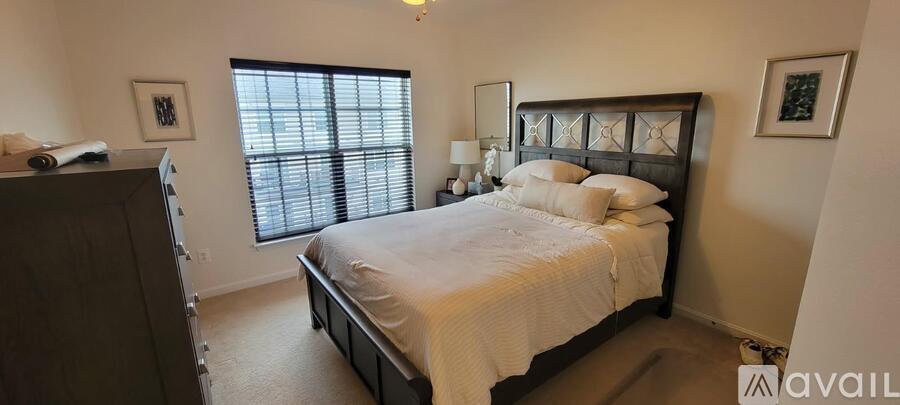 A bedroom with a large bed and a window with blinds.