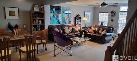 A living room with a purple chair and a black couch.
