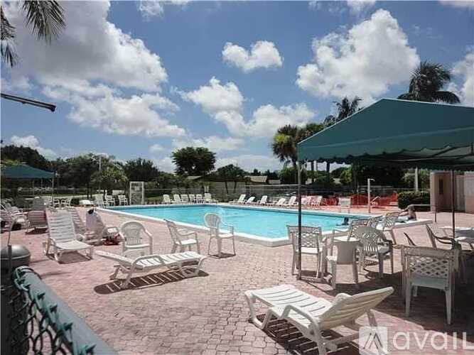 A pool surrounded by chairs and umbrellas.