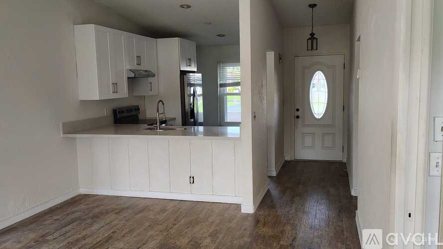 A kitchen with white cabinets and a wooden floor.