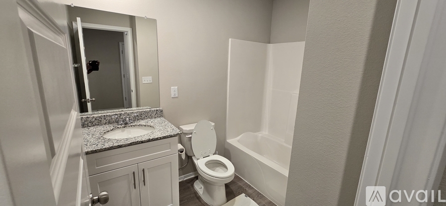 A bathroom with a toilet, sink, and mirror.