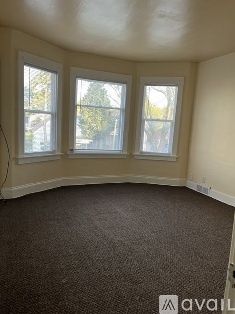 A room with carpeted floor and three windows.