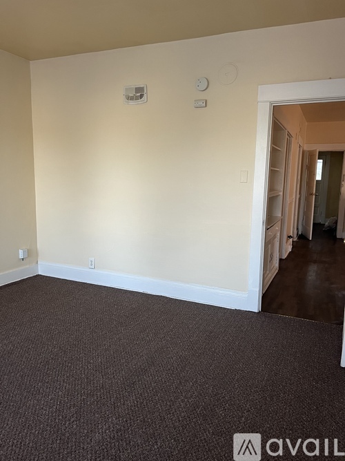 A room with a carpeted floor and a doorway leading to another room.