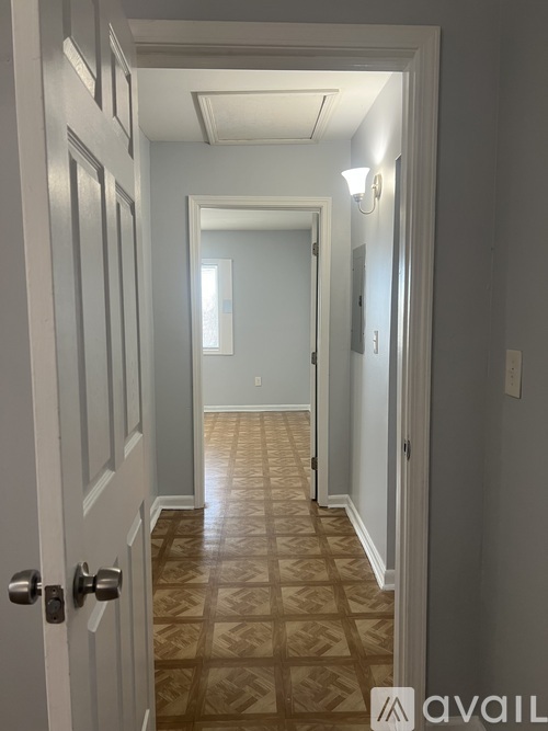 A hallway with a tiled floor and a door on the left.