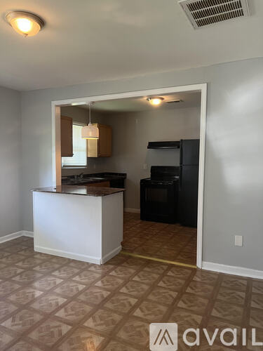 A kitchen area with a white counter and a black refrigerator.