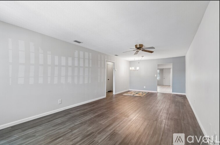 A spacious room with wooden flooring and a ceiling fan.
