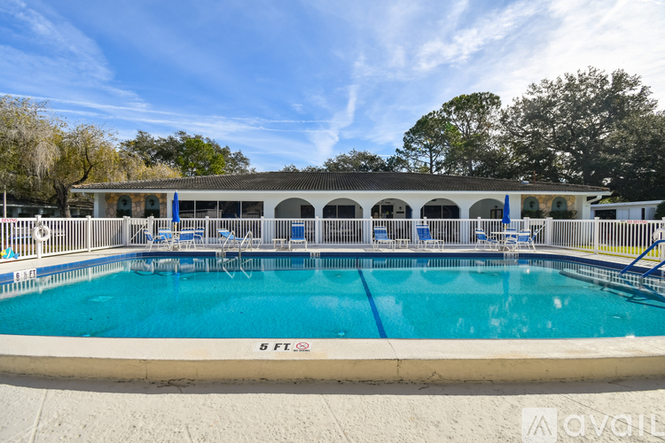A large outdoor swimming pool with a pavilion and lounge chairs.