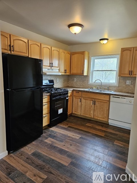 A kitchen with wooden cabinets and a black refrigerator.