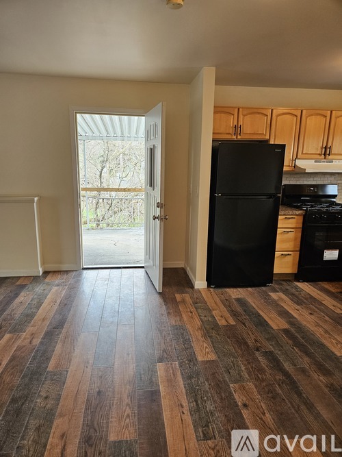 A kitchen with a black fridge and wooden floors.