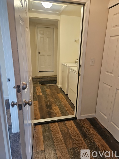 A hallway with a white door and a wooden floor.
