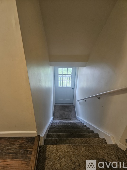 A staircase with a carpeted runner and a door at the top.