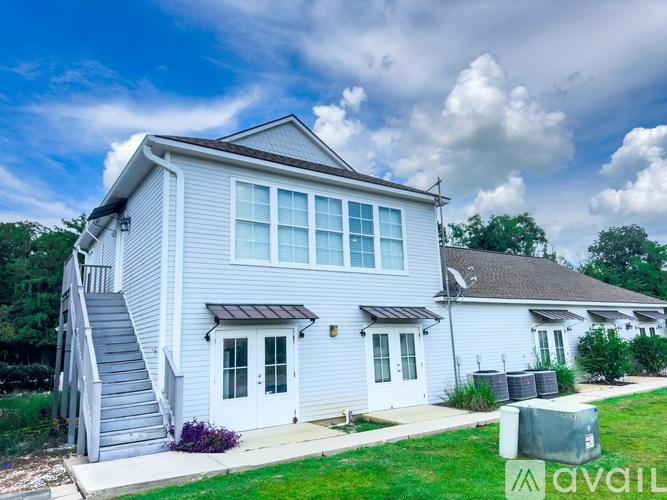 A house with a grey exterior and a white door is for sale.