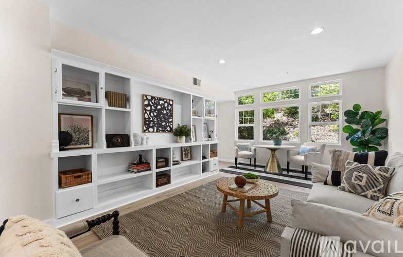 A living room with a white couch, a coffee table, and a large window with a view of the garden.