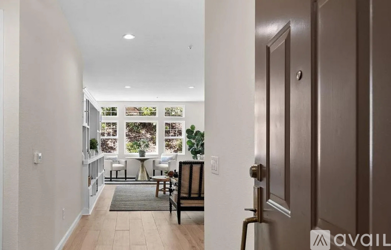 A hallway with a brown door leading to a dining area with a table and chairs.