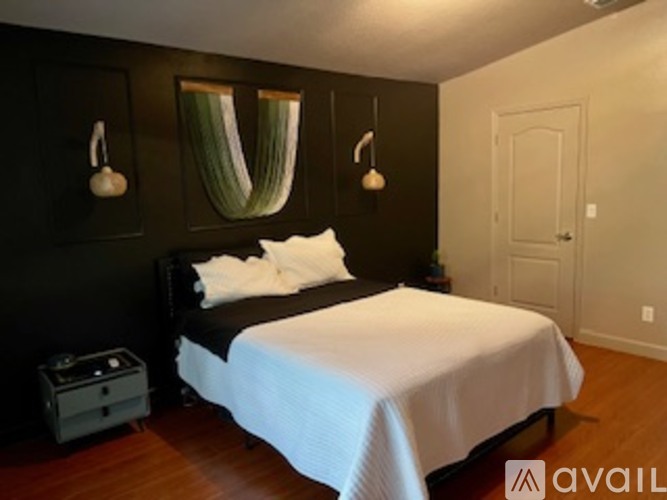 A bedroom with a bed, nightstand, and two wall sconces.