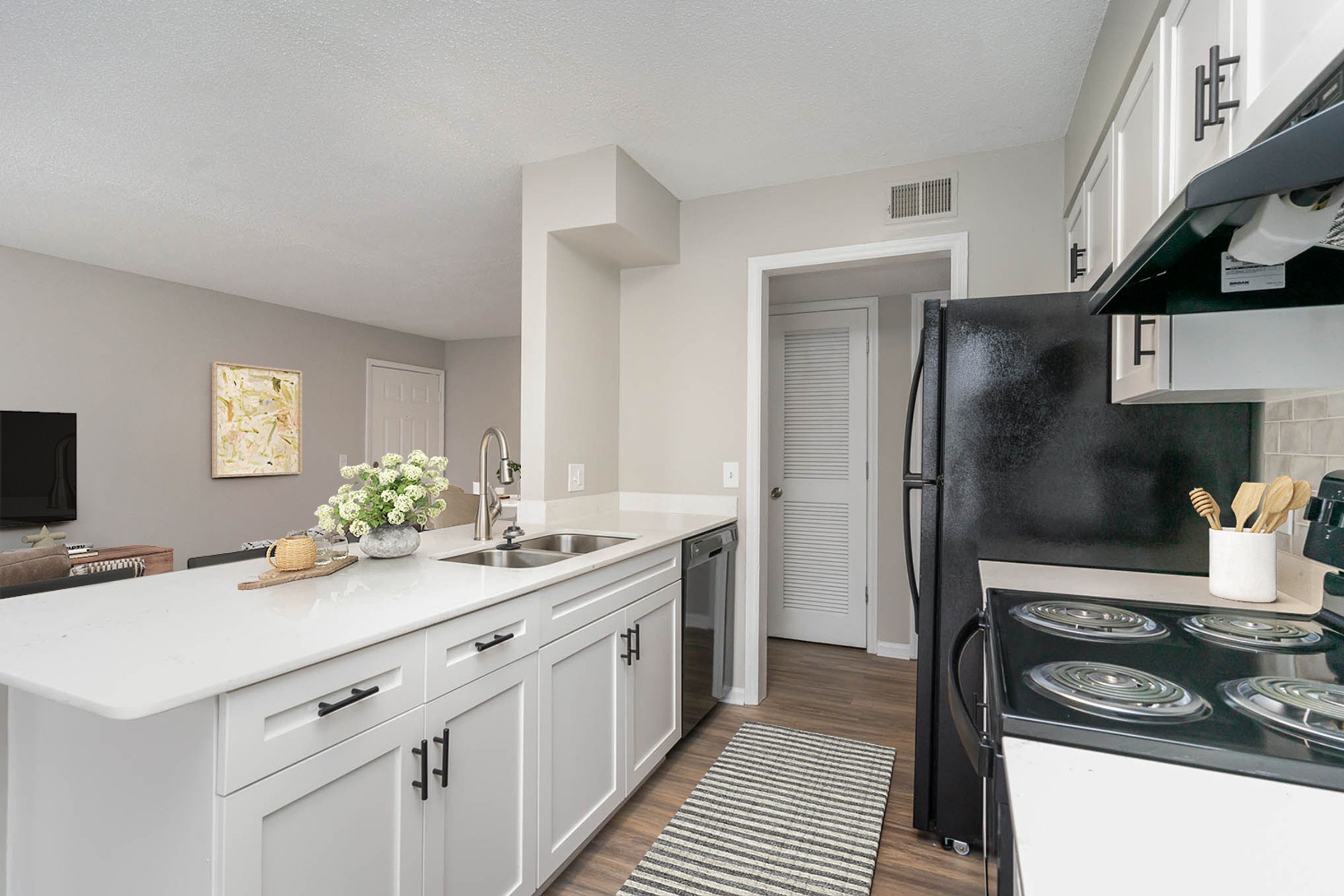 A kitchen with white cabinets and a black fridge.