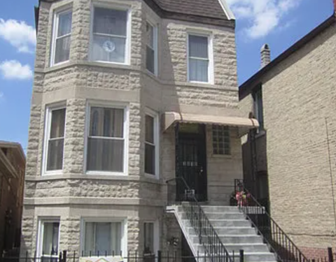 A large stone building with a black door and steps leading up to it.