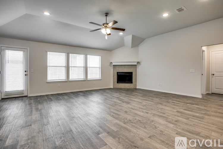 A spacious room with a fireplace and a ceiling fan.
