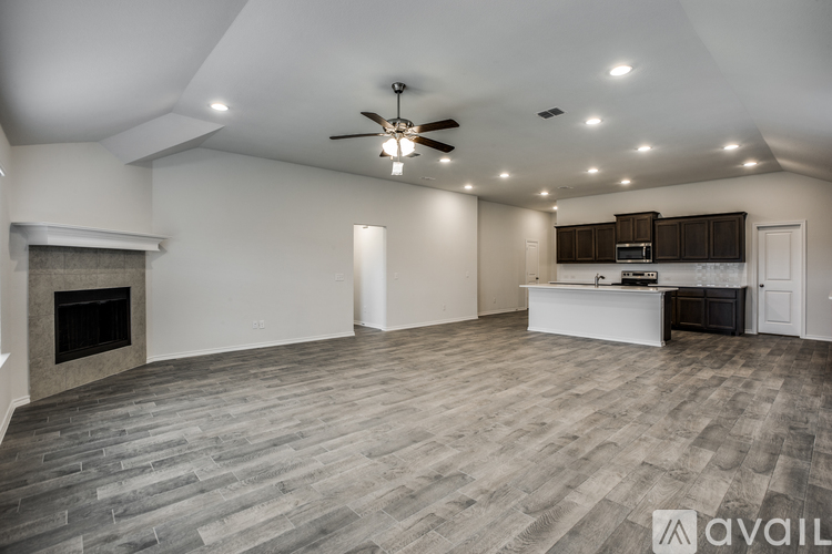 A spacious living room with a fireplace and a ceiling fan.