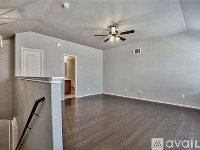 A spacious room with a ceiling fan and wooden flooring.