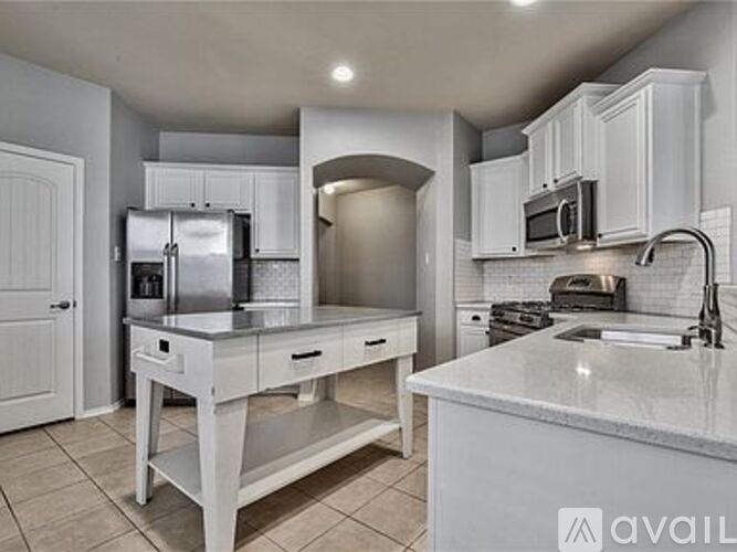 A kitchen with white cabinets and a marble countertop.